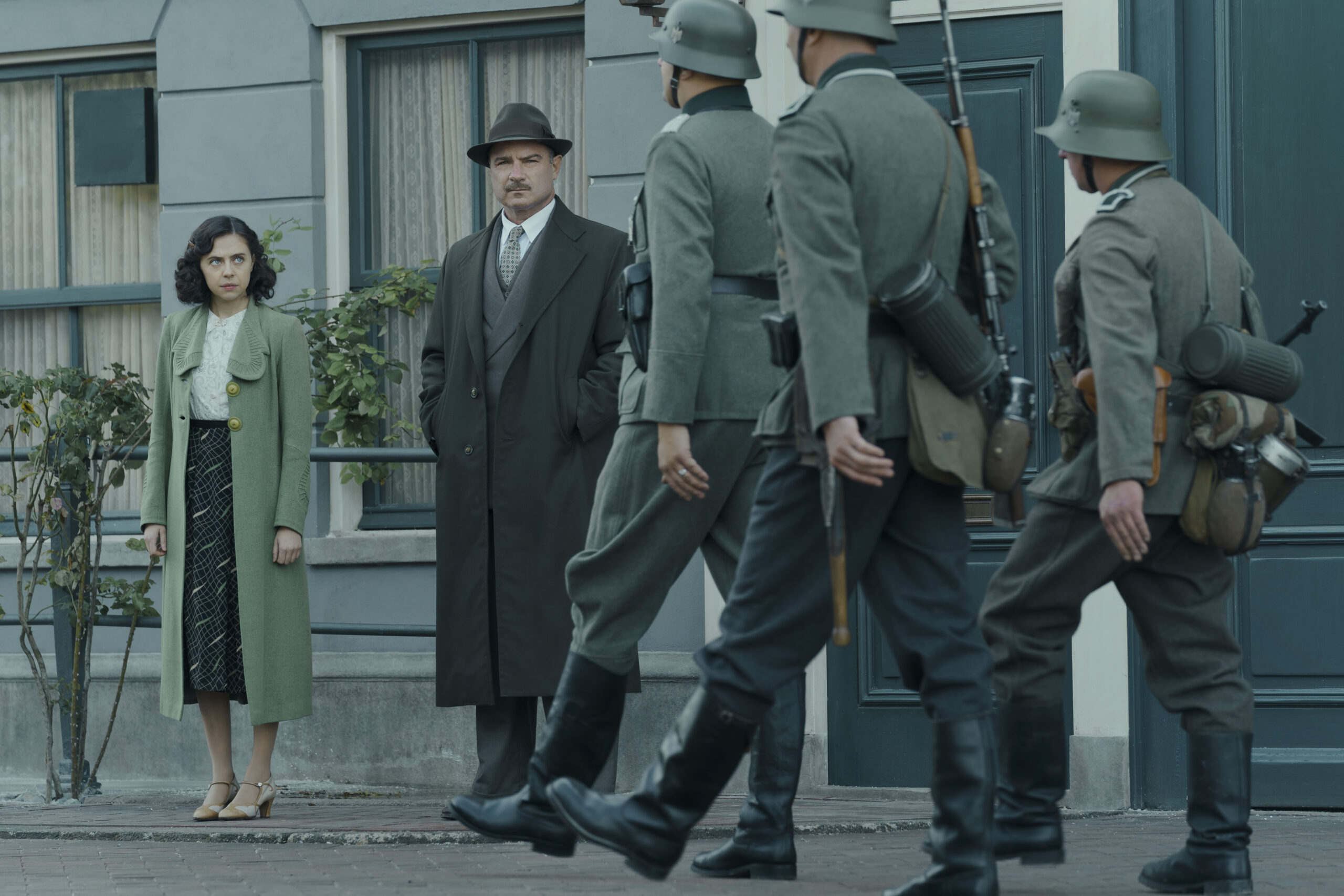 Miep Gies, played by Bel Powley, and Otto Frank, played by Liev Schreiber, watch as Nazi soldiers march down the street in Amsterdam in A SMALL LIGHT. 
